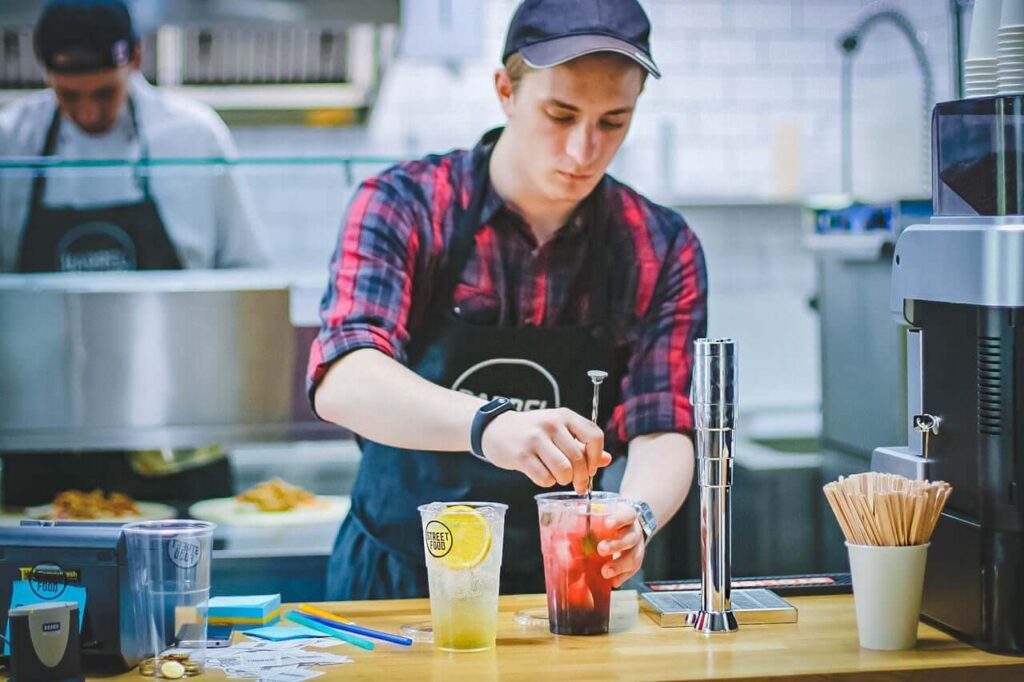 an employee working his hourly wage job making drinks at a restaurant