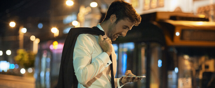 Salary businessman carrying his jacket and texting while walking at night
