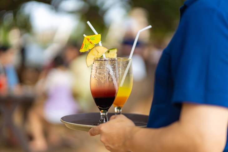 restaurant worker carries drinks for patrons