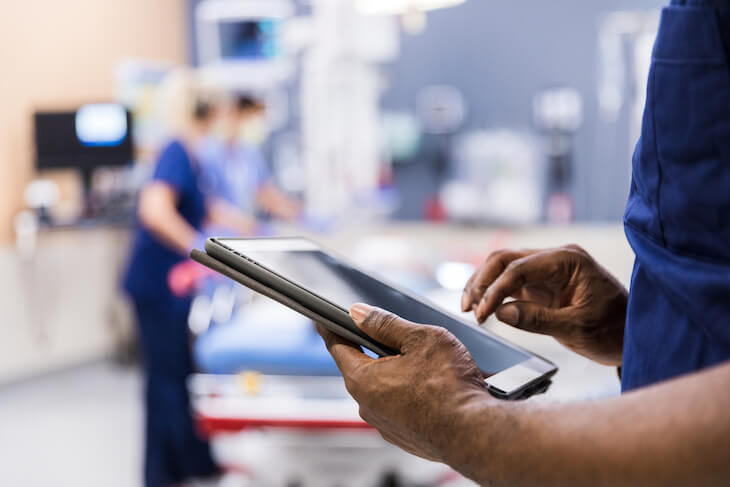 Healthcare workers in operating room with one holding tablet