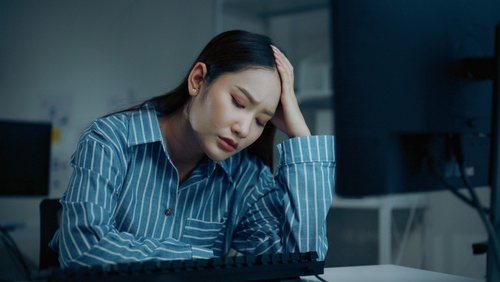 fatigued businesswoman resting head in hand while sitting at office desk